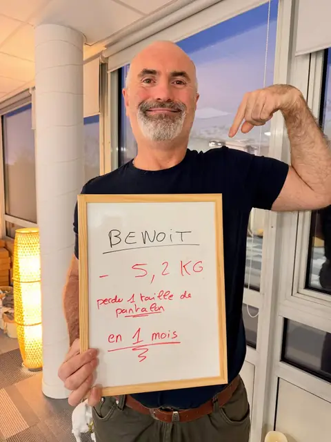 Souriant, un membre montre au club ce que dit son ardoise de bilan